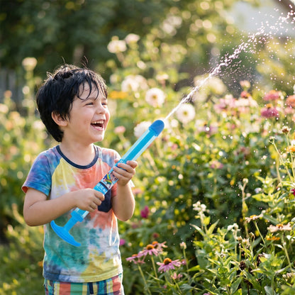 Kind spritzt mit der Feuerwerk-Wasserspritze im Garten