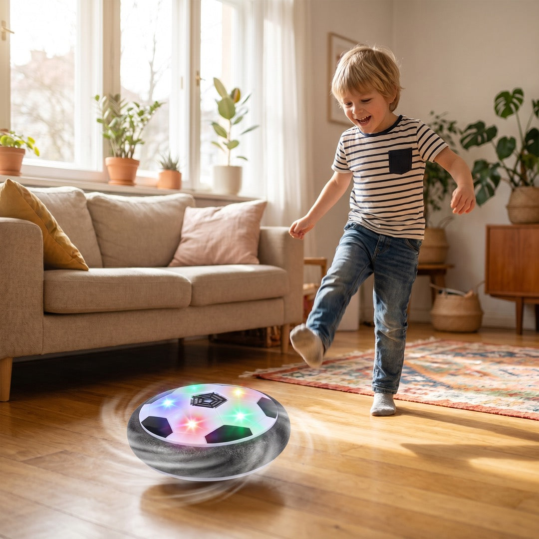 Junge kickt den schwebenden Fußball mit LED-Licht im Wohnzimmer