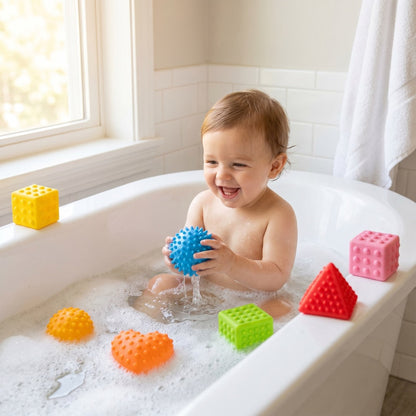 Baby spielt in der Badewanne mit den bunten Sensorik-Bauklötzen